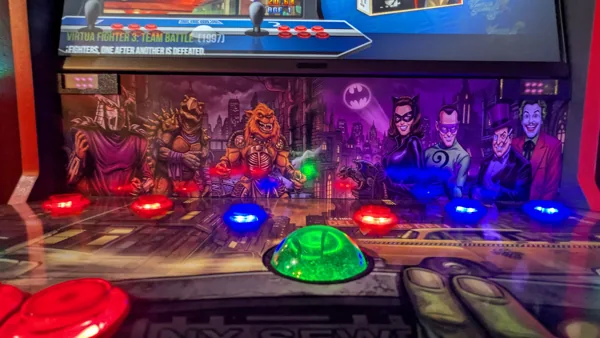 Green illuminated trackball beneath TMNT and Batman villain artwork