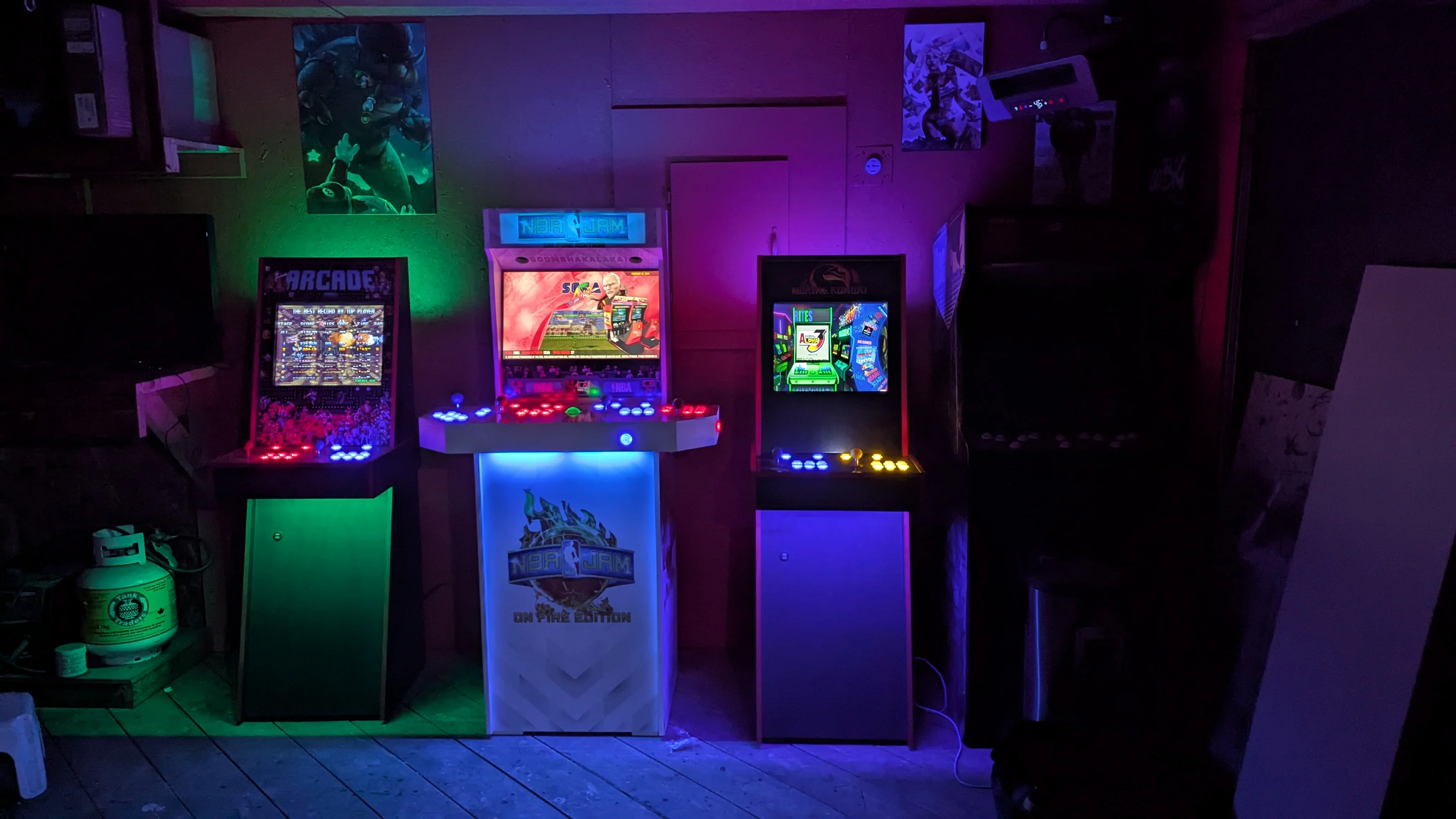NBA Jam and other custom arcade machines lit up in a dark arcade room