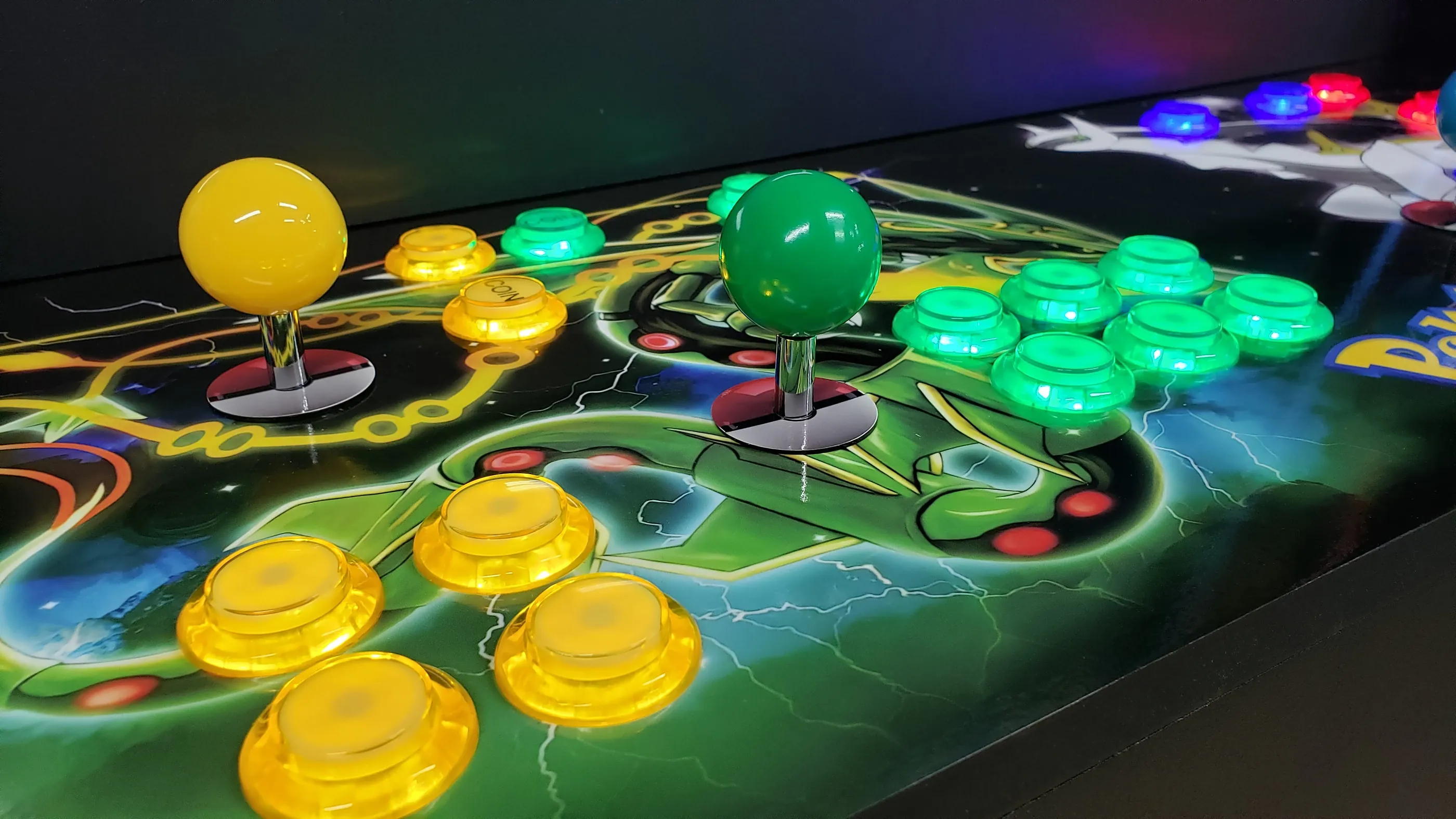 Close-up of yellow and green controls with Rayquaza artwork and Poké Ball joystick surrounds