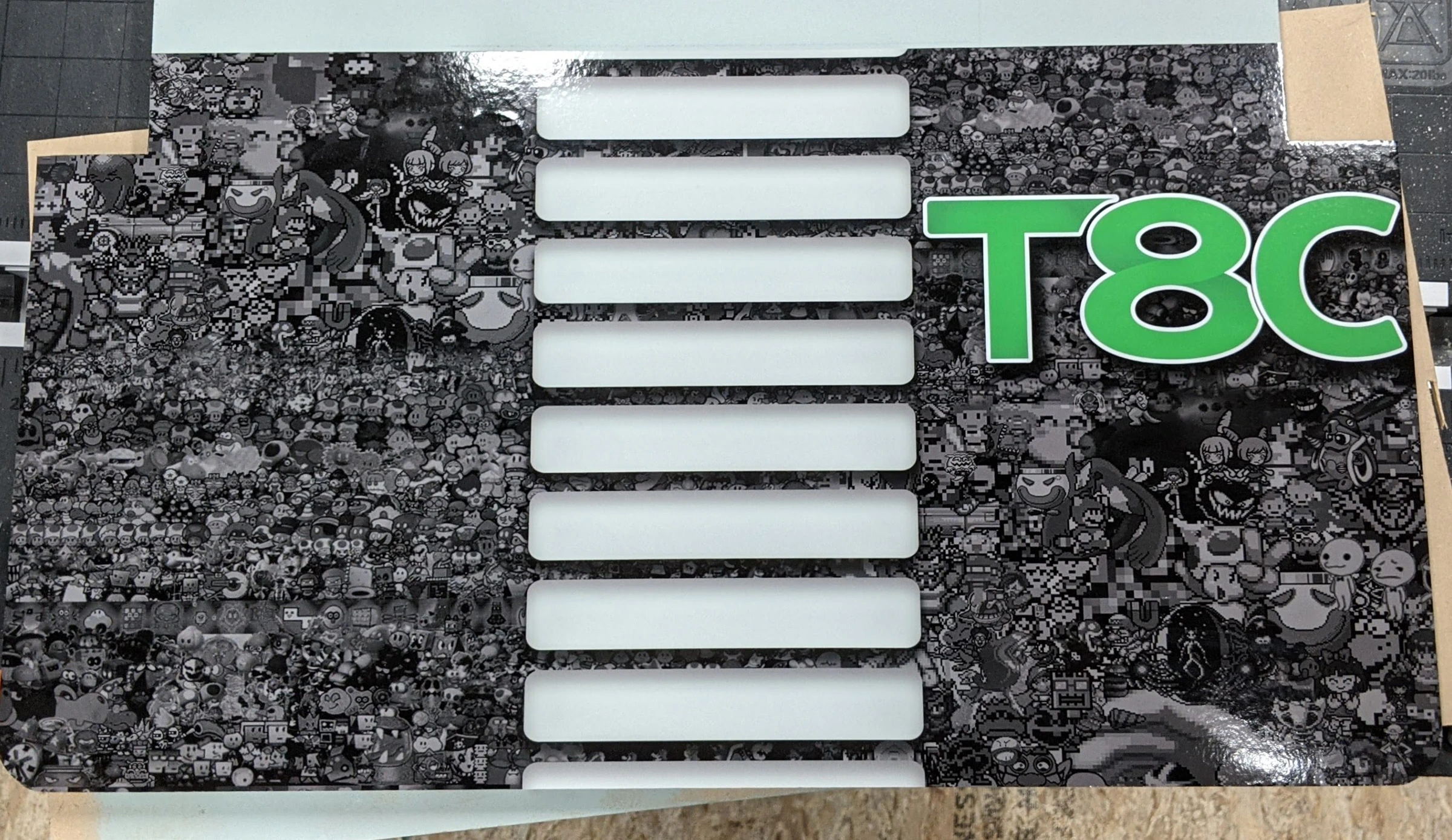 T8C control-panel artwork with a monochrome game-character collage before controls were installed